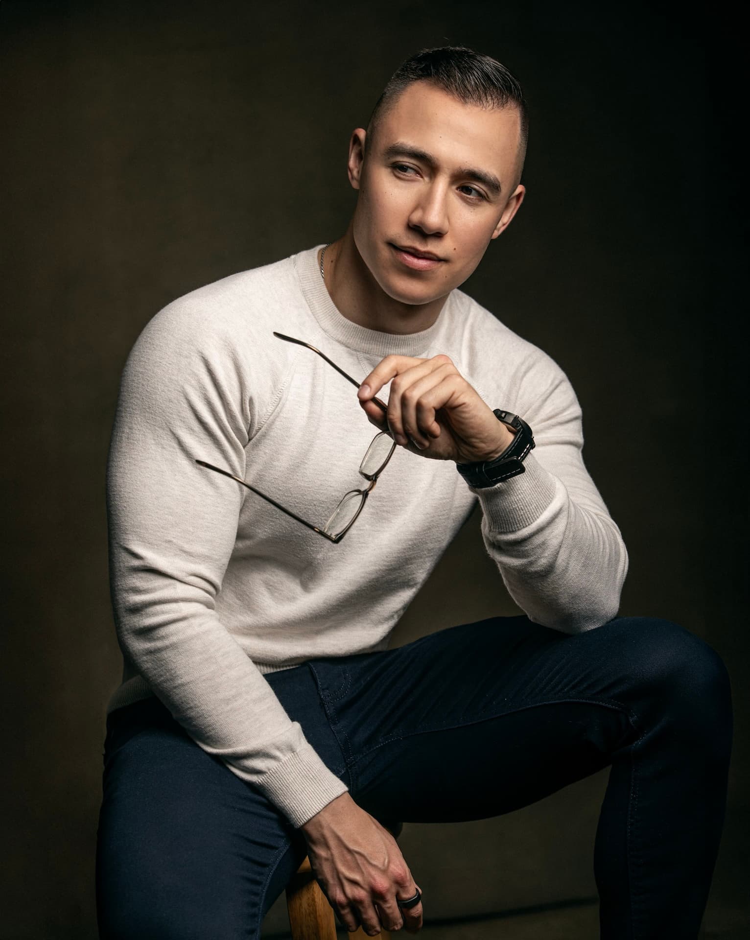 Joe Wanner, founder of SalesGym, seated and leaning forward with his glasses in one hand, looking off to the side.